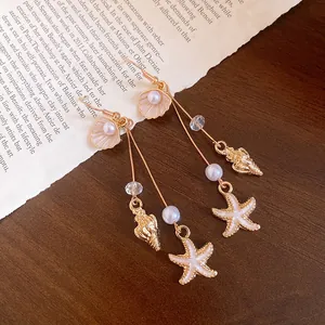Detail showing golden shell, starfish, and pearl charms on dangling earrings