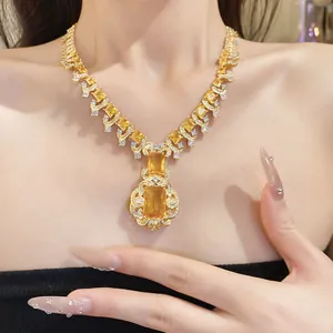 Gros plan collier doré avec pierres rectangulaires jaunes et détails floraux.