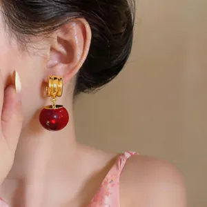 Detailweergave van luxe retro-oorbellen met grote rode harsbollen op een model