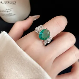 Dettaglio macro di un anello vintage con zircone verde smeraldo e motivi a piuma d'argento