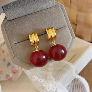 Gedetailleerd beeld van vintage gouden oorbellen met rode doorschijnende hars