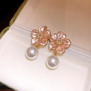 Detail shot of elegant pink enamel flower earrings with large white pearl drops.