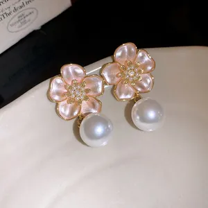 Detailed view of pink flower earrings with zircon center and dangling white pearl drop.