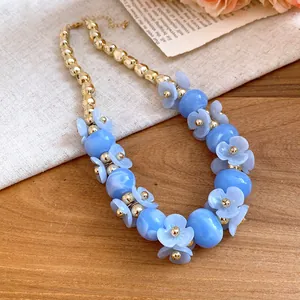 Detailed close-up of blue acrylic flower beads and gold metal spheres on necklace