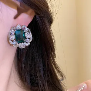 Gros plan d'élégantes boucles d'oreilles en zircon vert émeraude avec dentelle argentée.