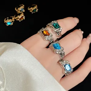 Elegant vintage irregular textured silver rings with colorful gemstones worn on fingers.