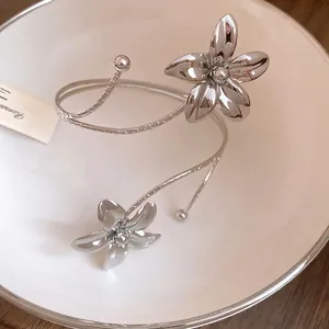 Elegant silver metal floral open arm cuff bracelet with double flower design displayed on plate
