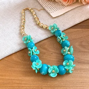 Close-up of acrylic flower beaded necklace with turquoise petals and blue beads.