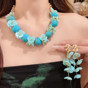 Close-up detail of acrylic blue beaded flower necklace and matching dangling floral earrings