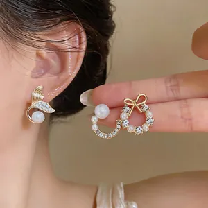 Close-up of pearl and rhinestone earrings featuring fish tail and bow wreath designs.