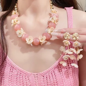 Close-up of pink acrylic flower necklace and matching dangling earrings on model's skin