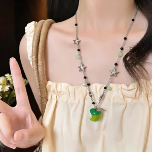 Detail of a sweet green enamel apple pendant necklace with star and pearl accents.