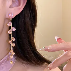 Primo piano di eleganti orecchini a goccia con zirconi rosa e design a foglia scintillante