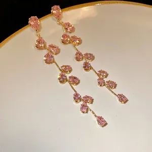 Dettaglio macro delle pietre di zircone rosa sui lunghi orecchini a nappa foglia d'oro
