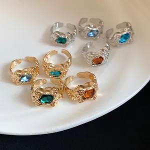 Detail shot of vintage irregular crinkle open rings with colorful gemstones on a white plate