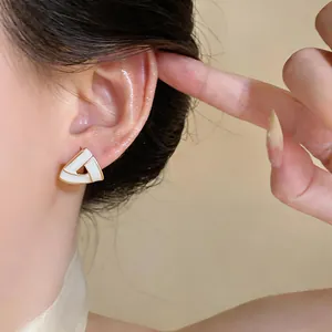 Detailed view of elegant gold-toned triangle enamel stud earring worn on model's ear