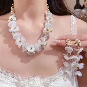 Detailed view of elegant white acrylic flower necklace and matching drop earrings on model