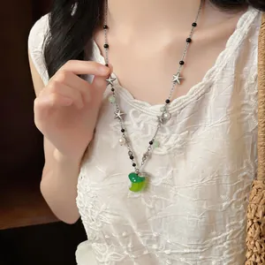Detail view of a fresh star pearl beaded necklace with a green apple pendant.