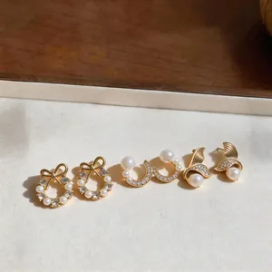 Detailed view of three pearl and rhinestone earring sets in bow and fishtail designs