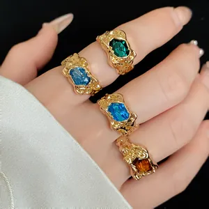 Detail of irregular wrinkled gold rings with colorful gemstones on fingers