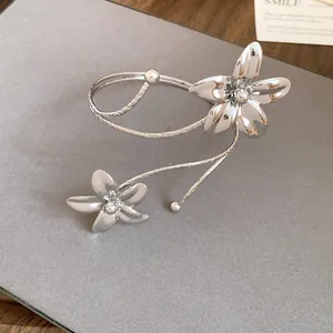 Detailed view of an elegant silver-tone metal wrap bracelet featuring two floral designs