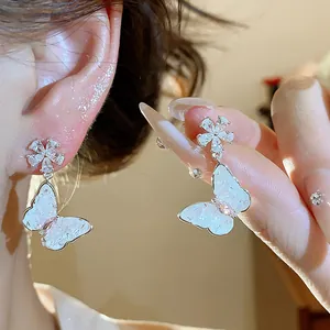 Primo piano di eleganti orecchini pendenti a farfalla e fiore con decoro in zirconi