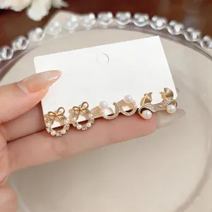 Detailed close-up of pearl and rhinestone earring set on white card held by hand.