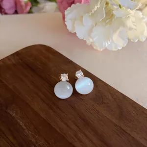 Close-up of minimalist cat eye stone stud earrings with sparkling zircon detail
