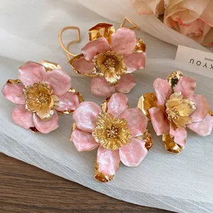 Detail view of retro metal oil-dripping pink flower stud earrings with golden centers