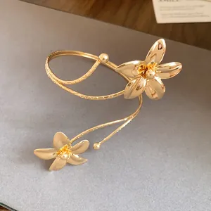 Elegant detailed view of a gold-plated metal flower open bangle and arm cuff jewelry piece.