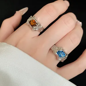 Close-up detail of irregular vintage rings with amber and blue gemstones on hand