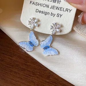 Dettaglio macro di orecchini a farfalla in argento S925 con zirconi blu brillanti.