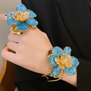Close-up of elegant blue and gold floral jewelry set featuring intricate enamel petals.