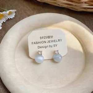 Elegant S925 silver needle stud earrings with zircon and cat eye stones on display.