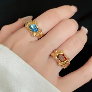 Close-up of irregular pleated gold rings with blue and amber gemstones on hand
