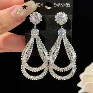 Detailed macro view of luxurious teardrop-shaped zirconia earrings on black display card