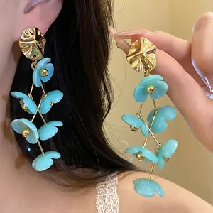 Close-up of elegant light blue acrylic flower dangle earrings with gold metallic tops