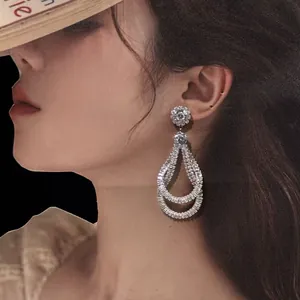 Detailed close-up of vintage palace-style zircon teardrop earrings worn by a model.