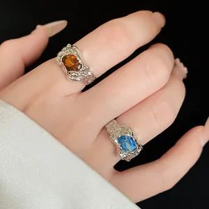 Close-up of vintage irregular wrinkled rings with amber and blue gemstones on hand