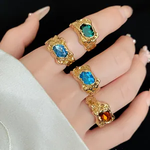 Detailed view of irregular geometric gold rings with colorful gemstones on hand