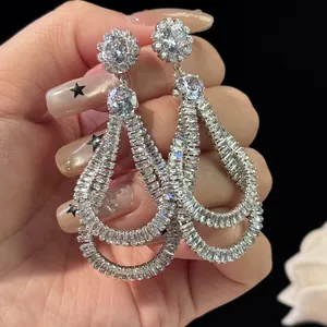 Macro view of teardrop zircon earrings with layered crystals and floral stud