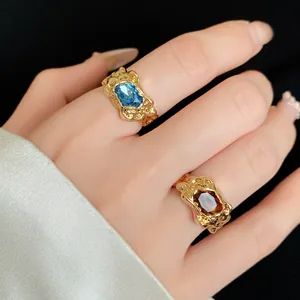 Detailed macro view of irregular pleated gold rings with blue and amber zircon stones
