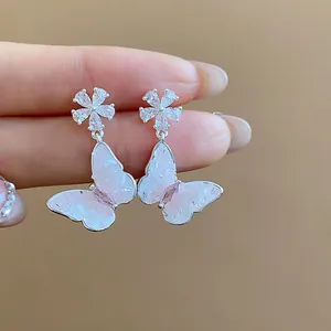 Vista dettagliata di eleganti orecchini a pendente con farfalla e fiore in zircone.