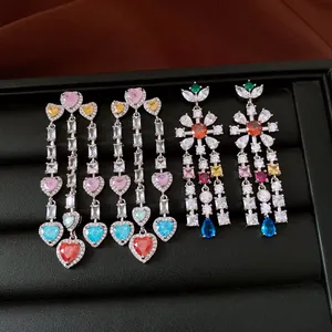 Detailed view of vintage-style flower and heart-shaped zircon tassel earrings on a tray