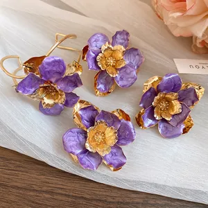 Elegant close-up of vintage purple enamel flower earrings with gold metallic centers.