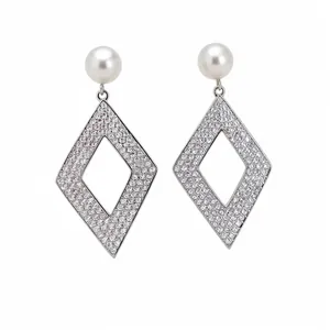 Boucles d'oreilles pendantes losange en zircon avec perles sur un fond blanc pur