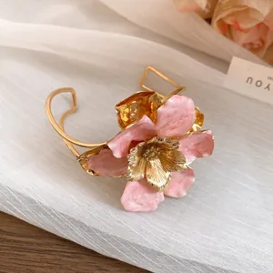 Detailed macro view of a vintage gold metal flower cuff bracelet with pink enamel petals