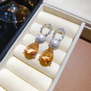 Nahaufnahme eleganter 18k vergoldeter Ohrringe mit champagnerfarbenen Birnensteinen und Perlen