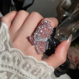 Detailed macro view of an intricate pink butterfly ring with micro-paved crystals