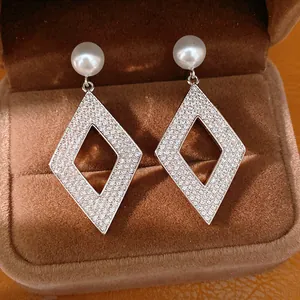 Gros plan de boucles d'oreilles losanges élégantes avec zircons brillants et perles